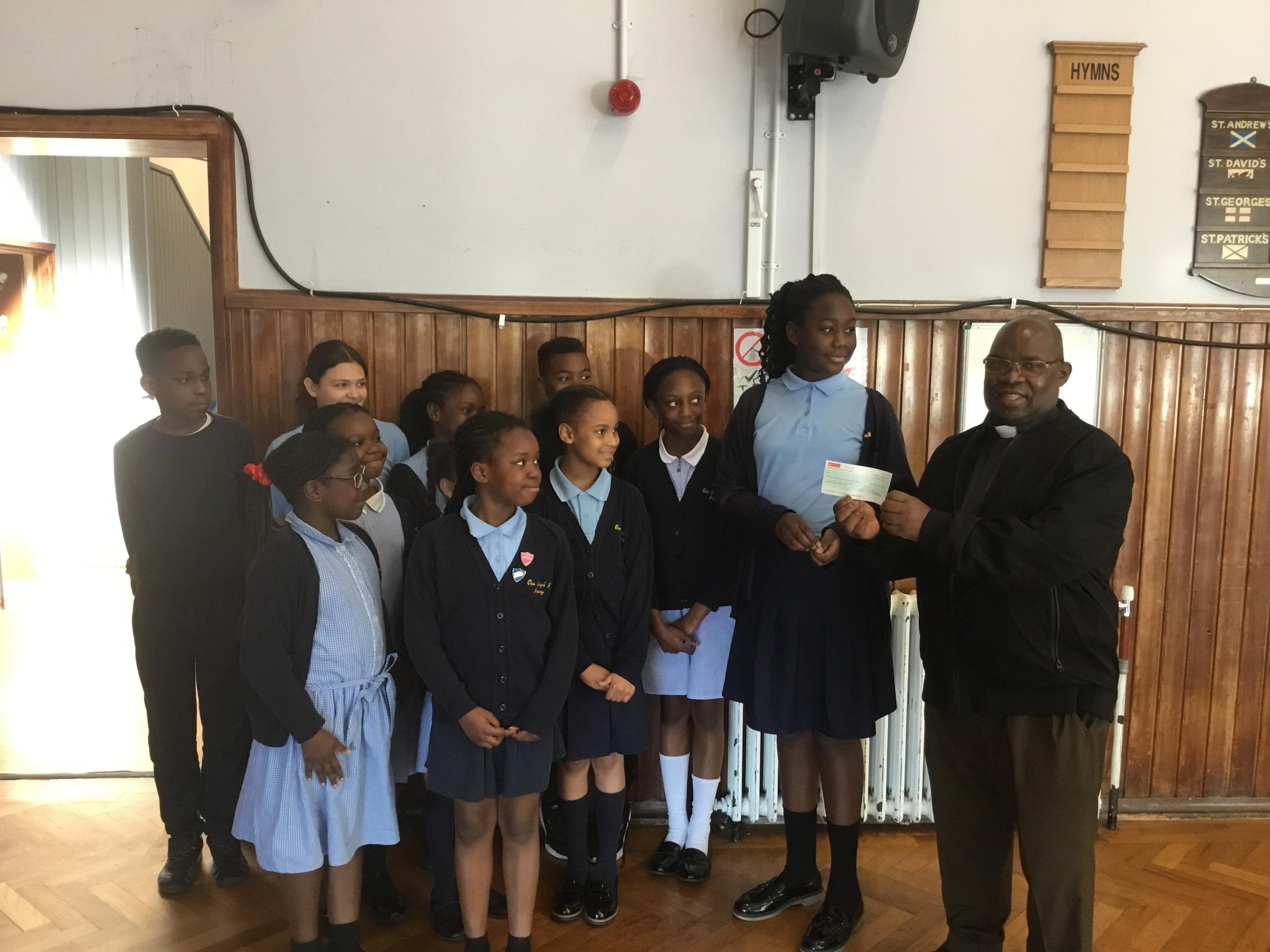 The RE leaders presenting Fr Henry with the money raised for his charity.